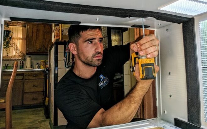 A window AC technician installing